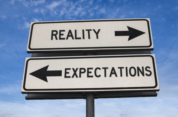 A street sign showing one way is reality and the other as expectations.