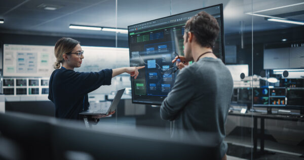Two IT people reviewing data on a monitor