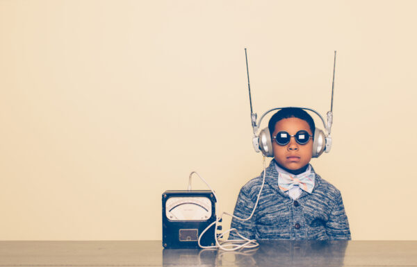 Young boy with sunglasses and headphones connected to a radio