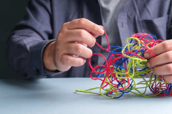 Man trying to untangle a knot of strings