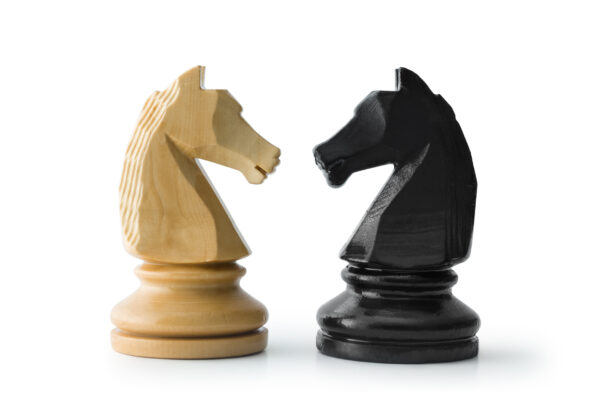 White knight chess piece next to black knight chess piece