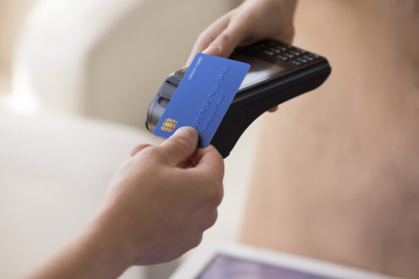 Person holding a credit card next to a handheld payment device