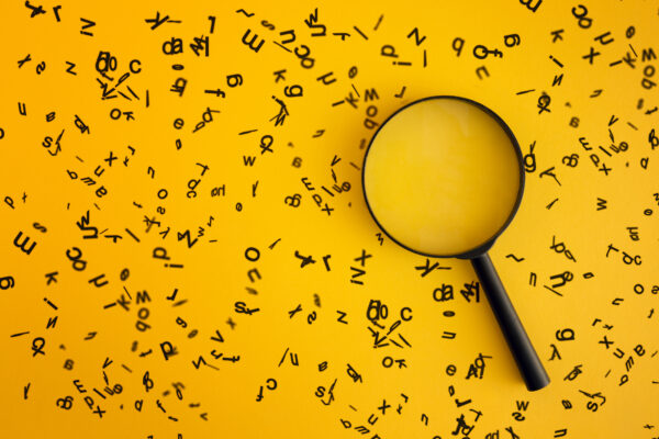 Magnifying glass on yellow background, with black letters all over the page