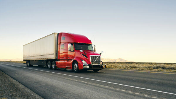 Red semi truck driving on a freeway