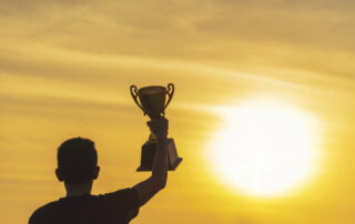 Young boy holding trophy at sunset