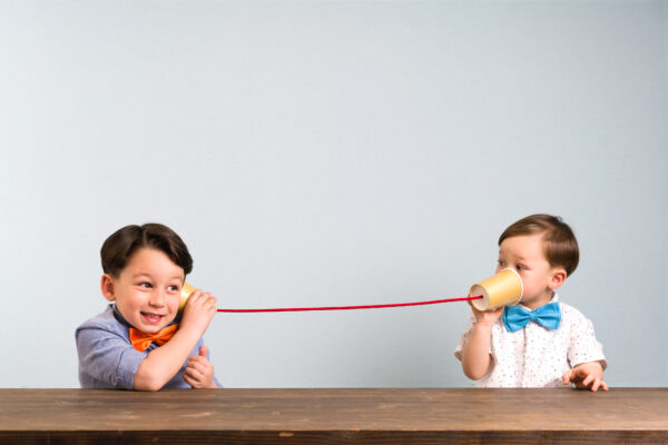 Two boys using cups and string to talk