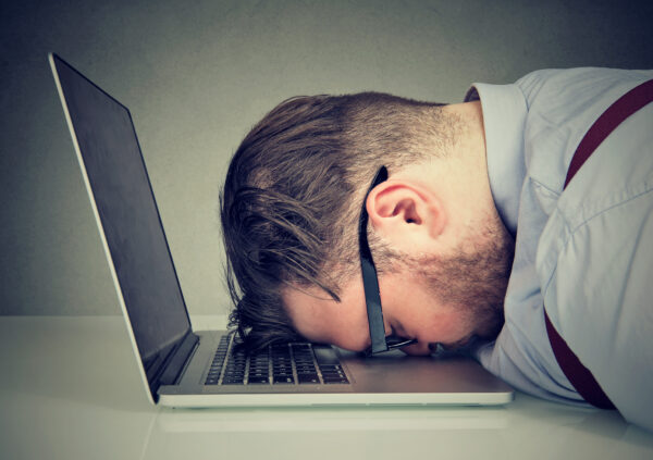 Man with head on laptop because he's overworked