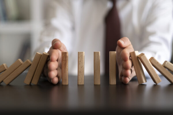 person using his hands to stop dominoes from falling