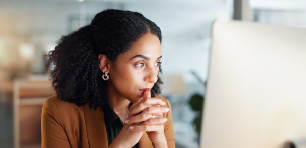 woman at a computer in an office, thinking