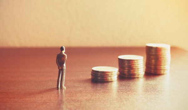 Toy miniature businessman looking at gold coins