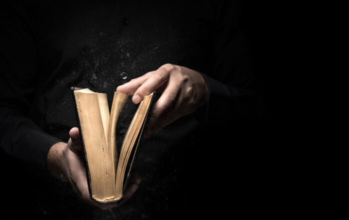 person holding an old book, dark background