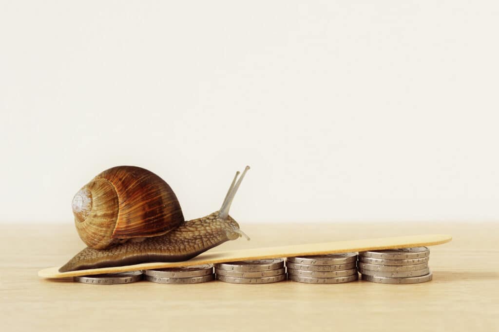 Snail climbing pile of coins – Concept of slow economic growth