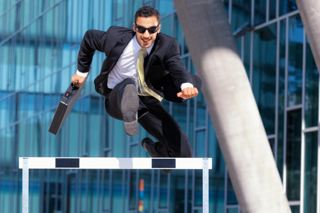 clever dynamic business hurdler businessman jumping over hurdle
