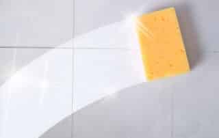 Cleaning concept trace yellow sponge on a dirty gray wall tiles. Horizontal composition.