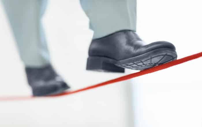 Unstable job - Low section of a business person walking on thin red line