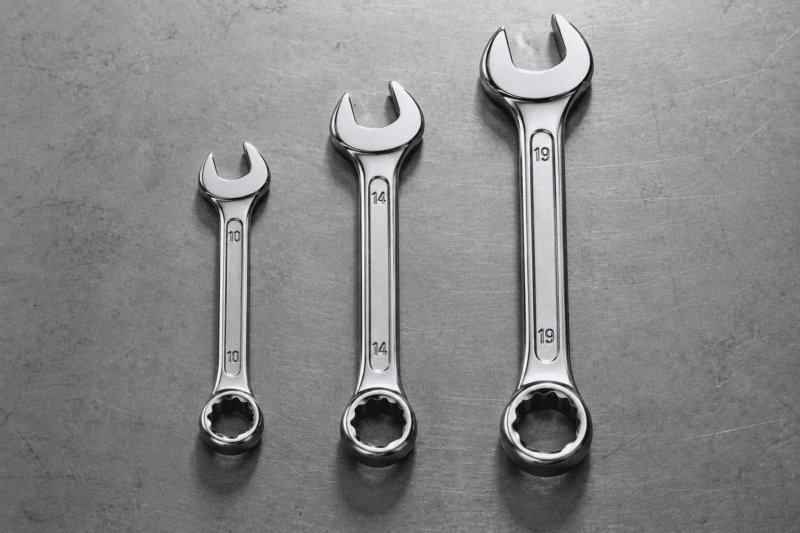 Three wrenches of increasing size laid out in a row on a clean workbench